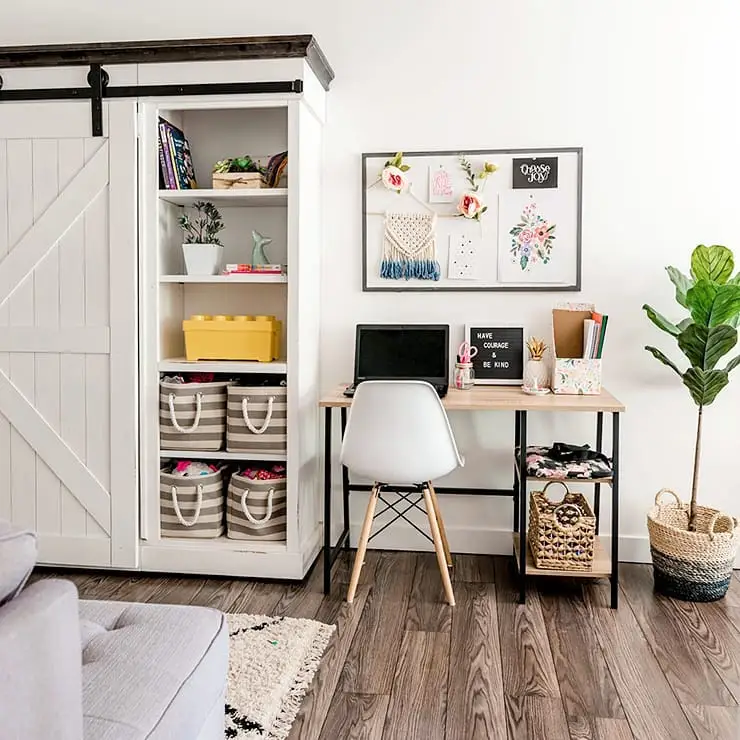 Small homework desk beside a tall storage cabinet with shelves, baskets, and school supplies