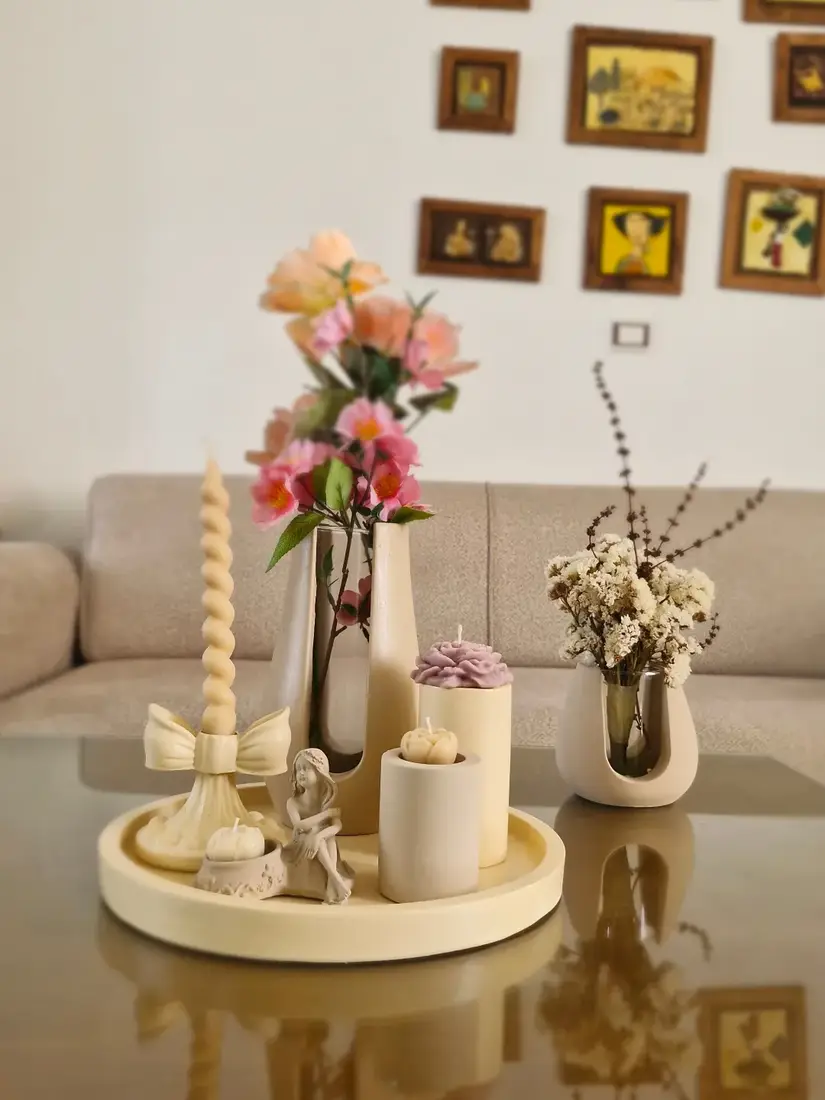 Cream coffee table tray with sculptural candles, twisted taper candle, bow candleholder, and pink flowers