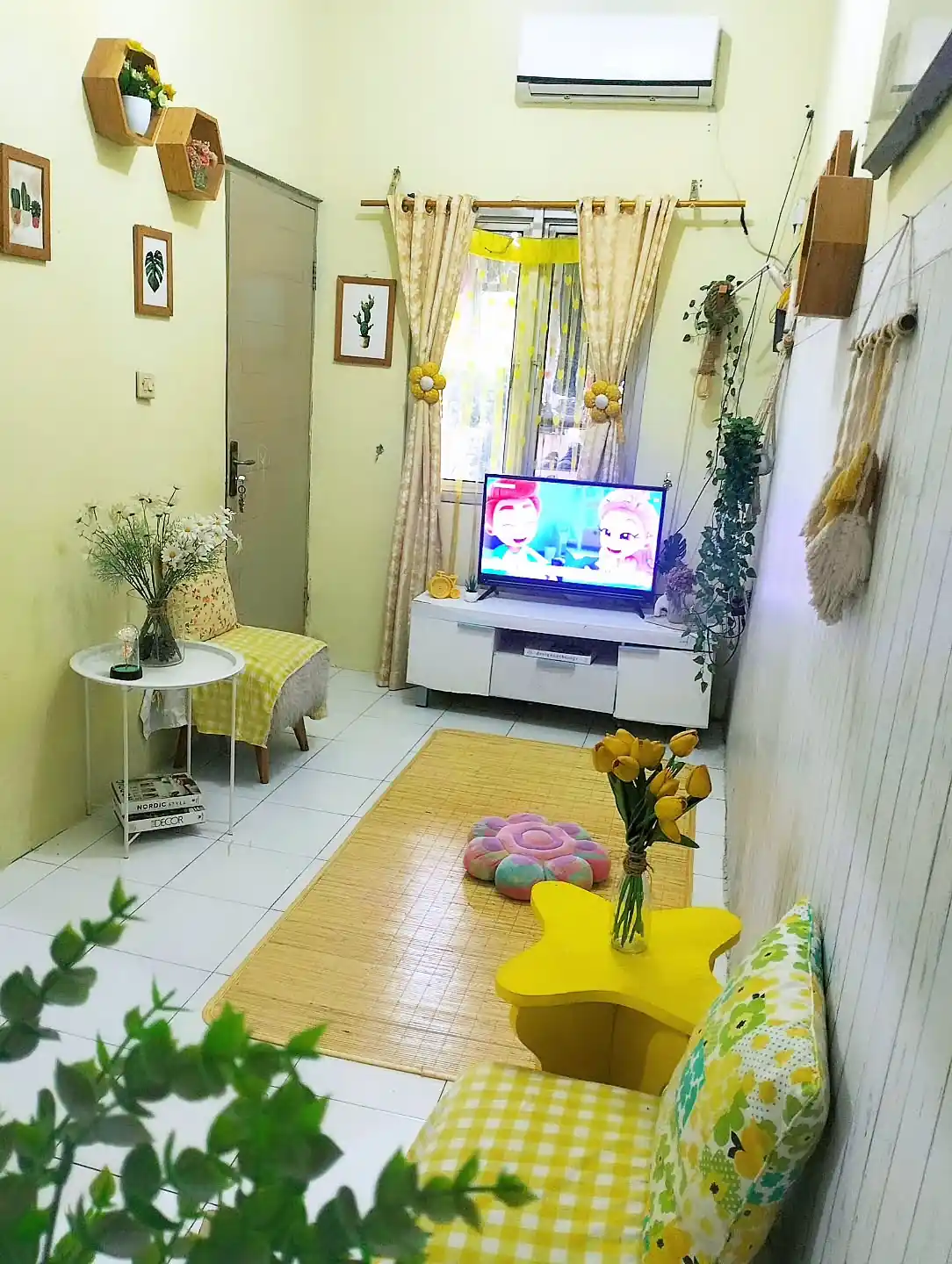 Colorful narrow living room with a tall bookcase wall, gallery art, patterned rug, and compact seating