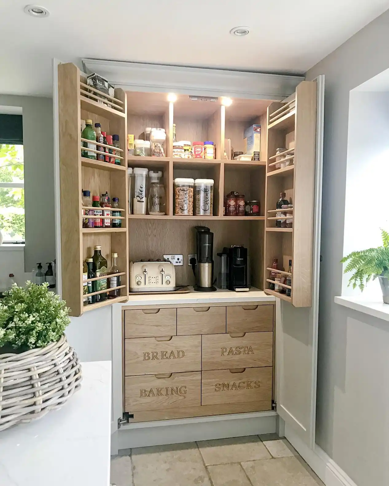 Pantry cabinet with narrow door racks holding small bottles and seasonings beside deep shelves with jars and appliances