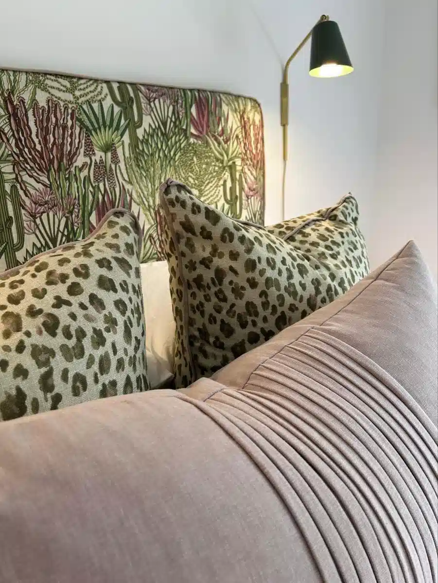 Olive green leopard print pillows paired with a botanical headboard and dusty pink cushion