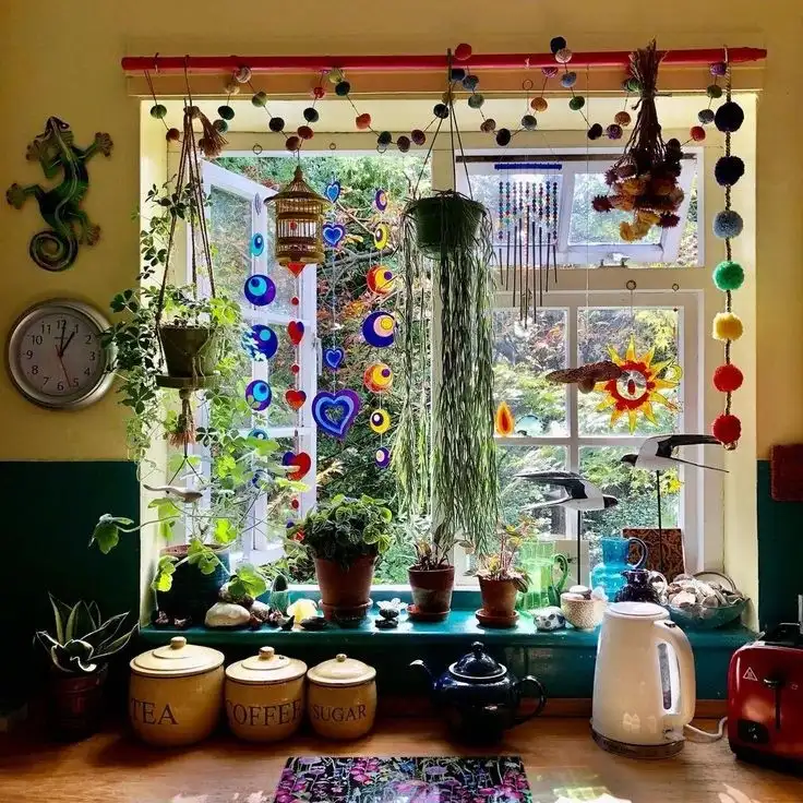 Colorful kitchen window with hanging beads, pom-pom garland, ornaments, and potted plants