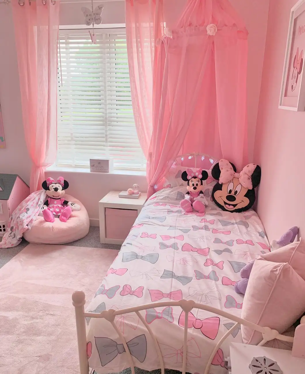 Pink and white girls bedroom with Minnie Mouse bedding, toys, canopy, and soft pink curtains