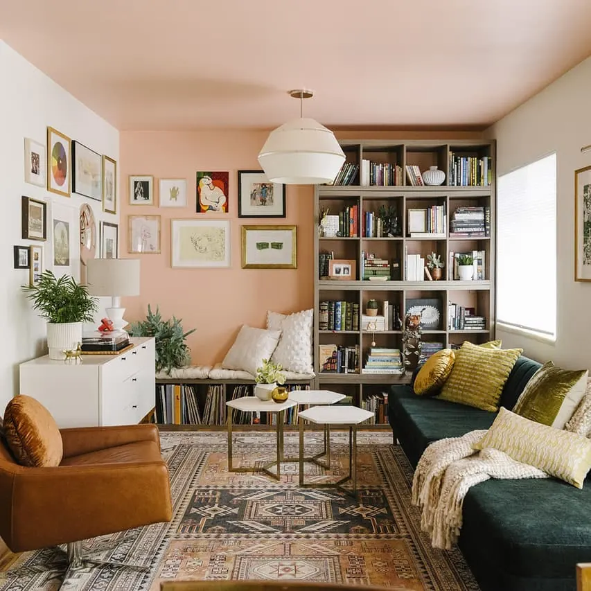 Bright narrow living room with white seating, a large pale rug, round coffee table, and floor-to-ceiling windows