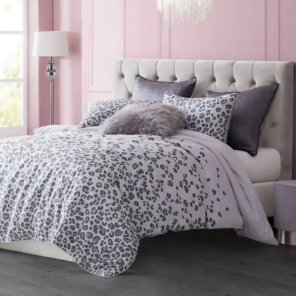 Gray and white leopard print bedding in a soft pink bedroom with a tufted headboard