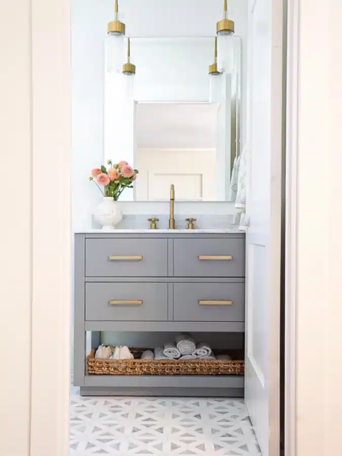 09 Gray bathroom vanity with drawers and a long woven basket filled with rolled towels underneath