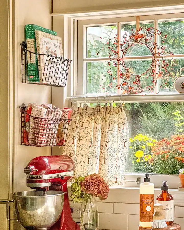 Fall kitchen window with berry wreath, warm café curtain, dried flowers, and seasonal decor