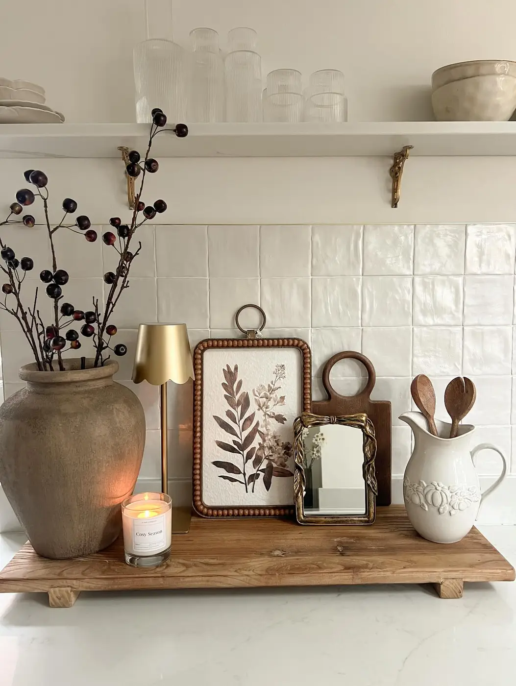 Neutral kitchen counter display with rustic vase, botanical art, small mirror, candle and wooden riser