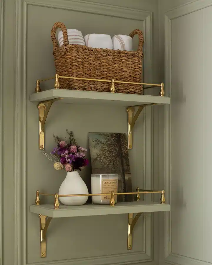 10 Two wall shelves with brass rails, a woven towel basket, flowers, framed art, and candle