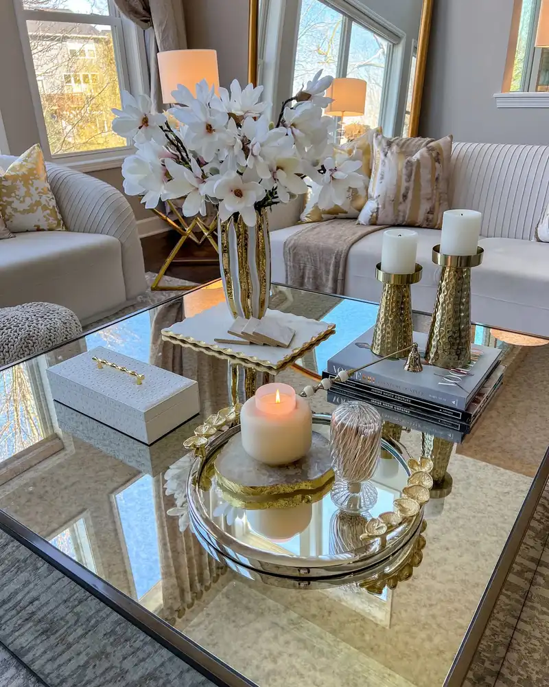 Luxury coffee table tray with gold candleholders, white flowers, candles, mirrored accents, and stacked books