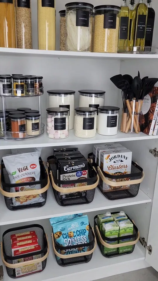 Organized pantry using turntables for spices, clear canisters for dry staples, and baskets for snacks and loose packets