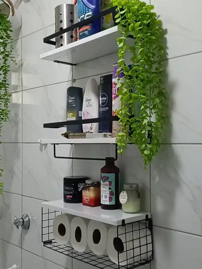 11 Black metal wall storage unit above a toilet with shelves, bottles, plants, and toilet paper basket