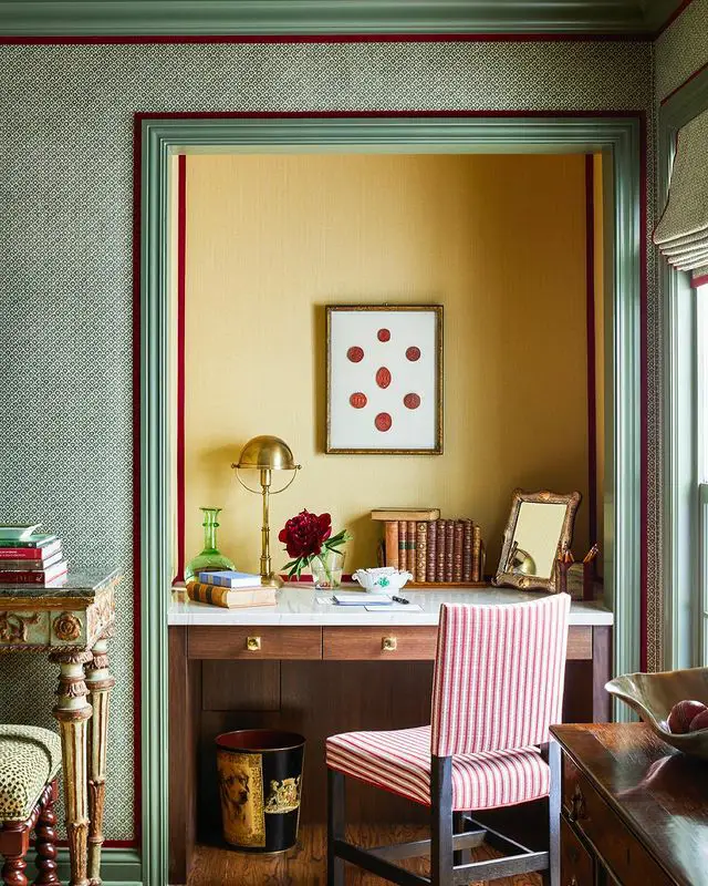 Small homework desk fitted inside a shallow wall recess with drawers, lamp, and framed artwork