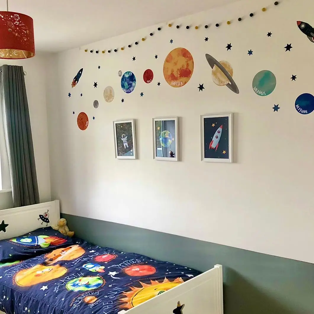 Colorful kids bedroom with painted planets on a white wall and matching solar system bedding