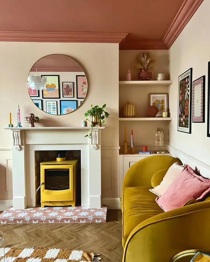 Warm colorful living room with mustard sofa, yellow stove, cream walls, dusty pink ceiling, and natural wood details