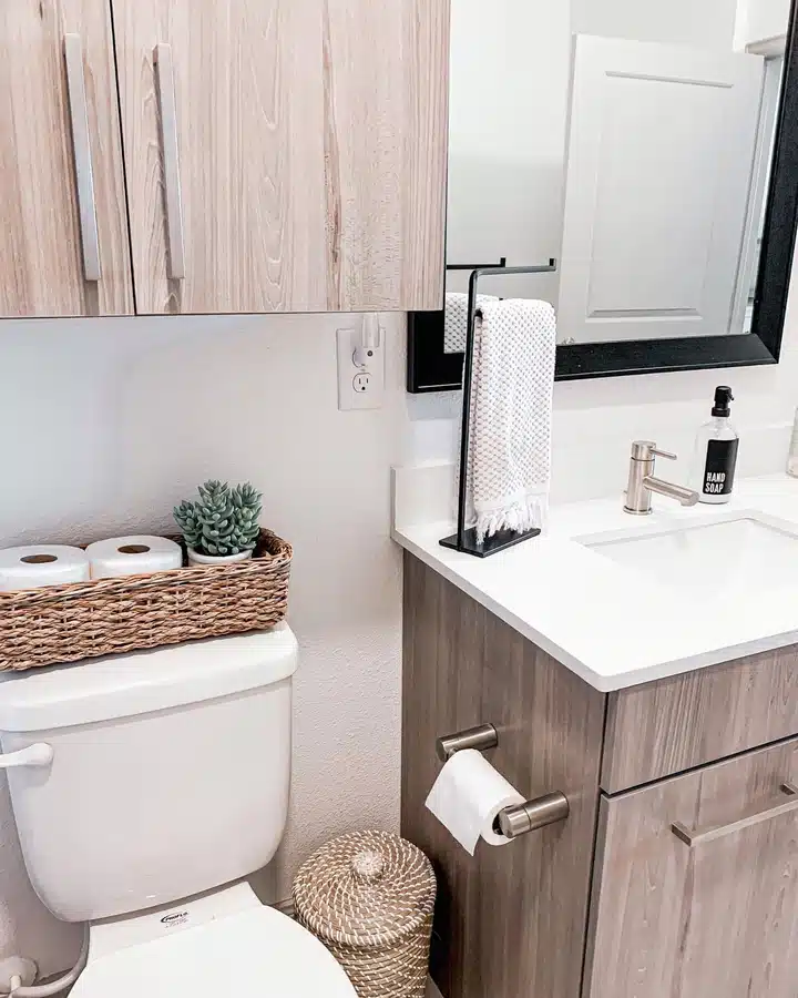 12 Small powder room with cabinet above toilet, vanity drawers, and woven basket holding spare toilet rolls
