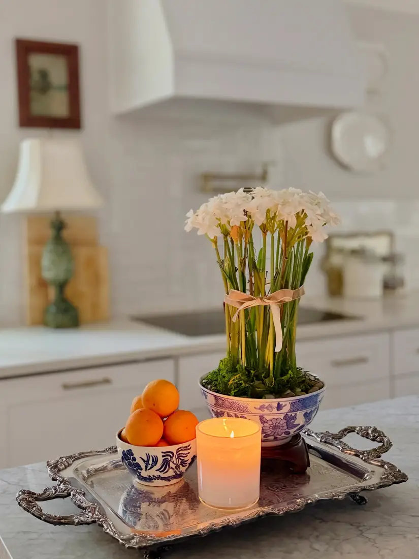 Silver coffee table tray with blue and white bowls, oranges, candle, and floral arrangement