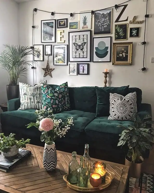 Dark green sofa beneath a gallery wall outlined with warm string lights for a cozy evening look.