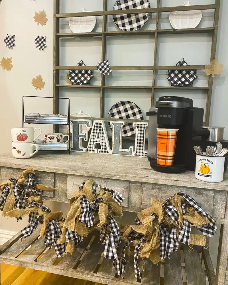 Black and white fall coffee station with checkered plates, fabric garland, patterned leaves, and orange accents