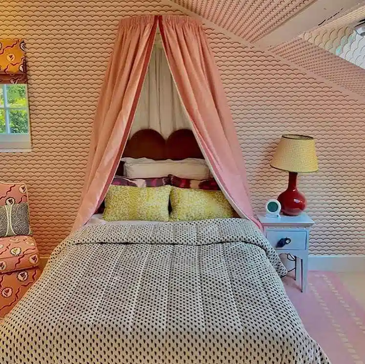 Small-scale leopard print bedding beneath a pink canopy with yellow accent pillows