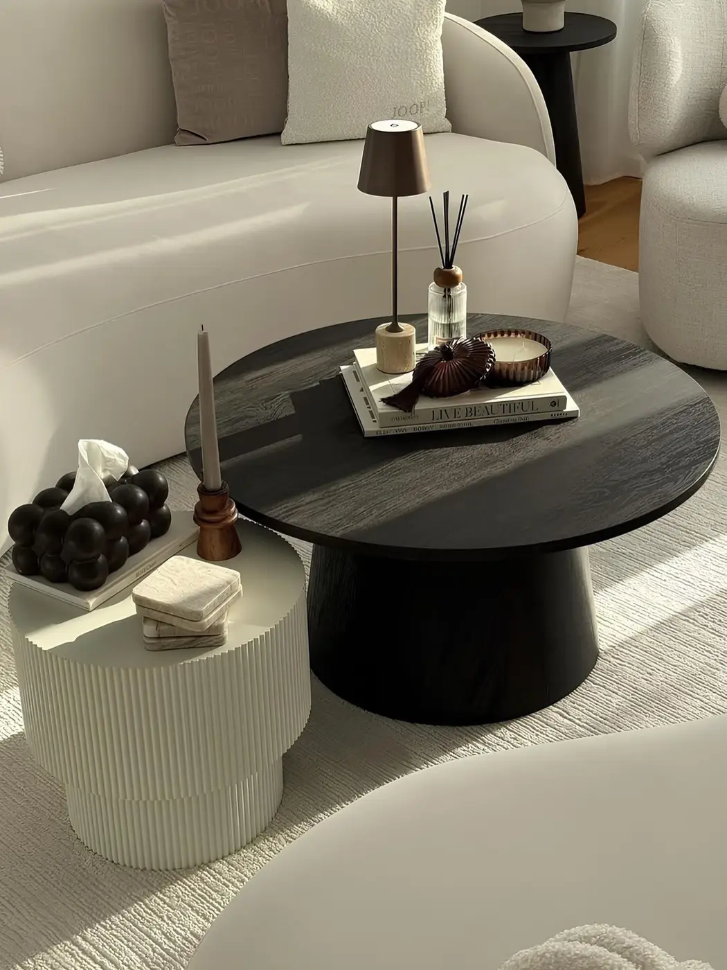 Black and cream nesting coffee tables styled with lamp, diffuser, books, candles, and everyday accessories