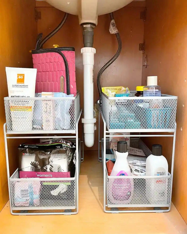 Under sink bathroom cabinet with matching two-tier mesh baskets positioned on both sides of the drainpipe