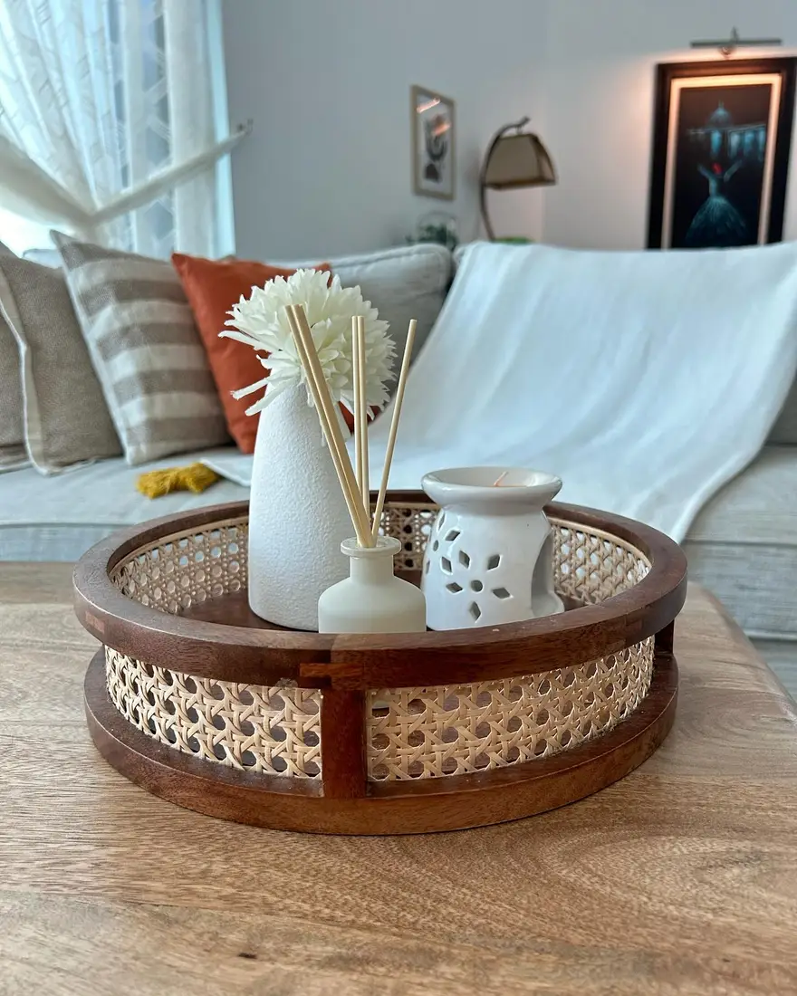 Wood and cane coffee table tray with white vase, reed diffuser, and ceramic warmer