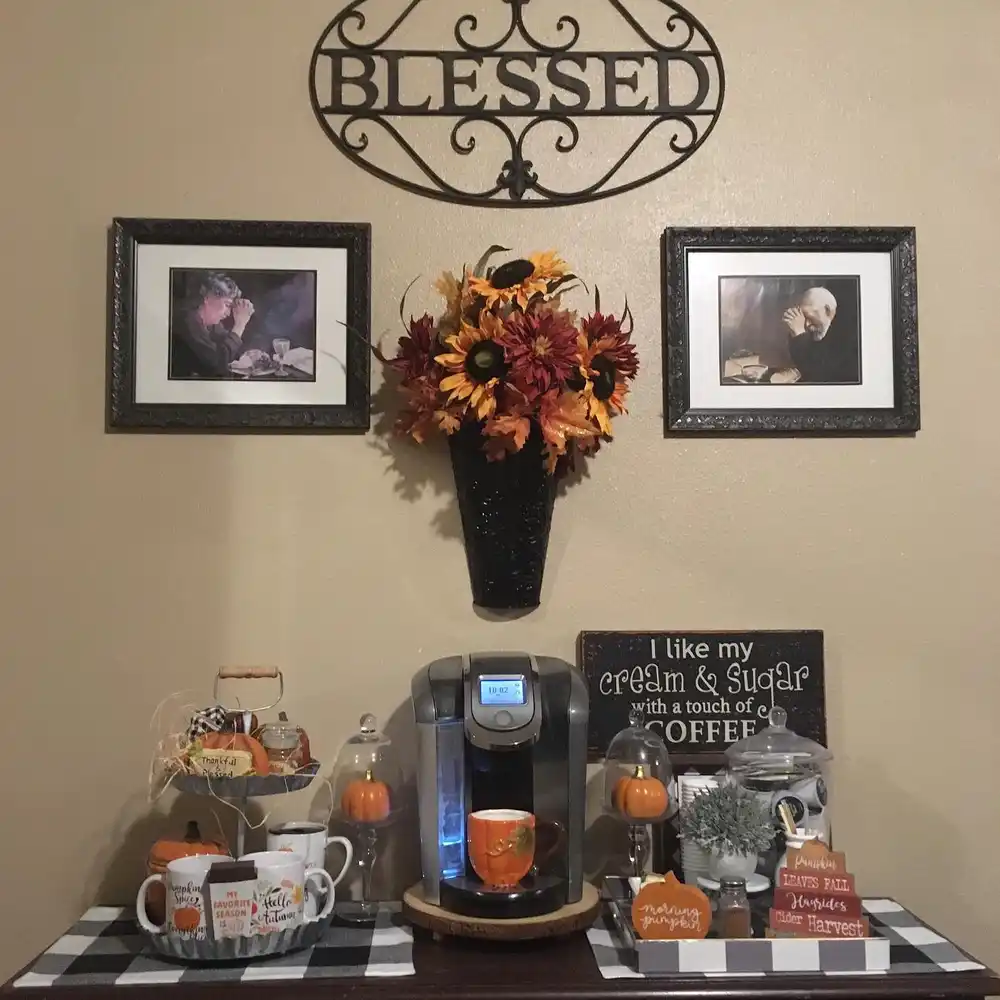 Fall coffee station with black and white checked runner, orange mugs, pumpkins, fall flowers, and framed wall decor