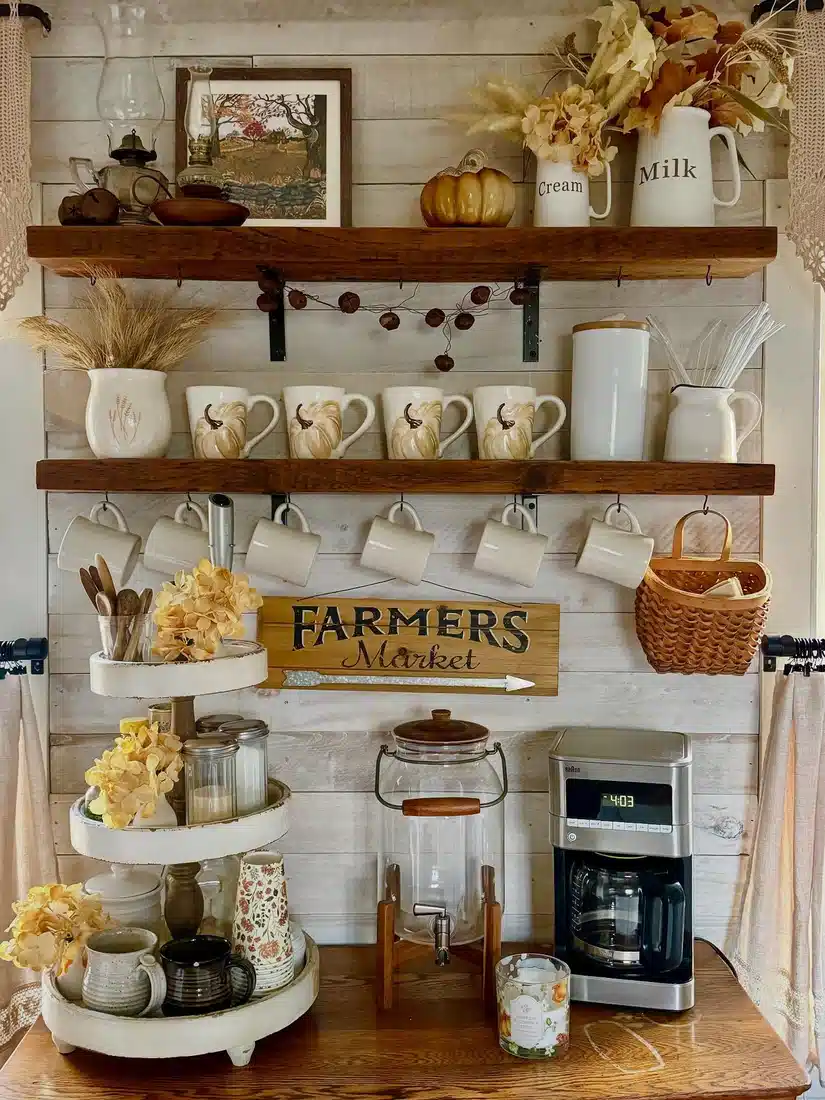 Fall farmhouse coffee bar with pumpkin mugs, dried flowers, wheat stems, wood shelves, tiered stand, and seasonal coffee decor