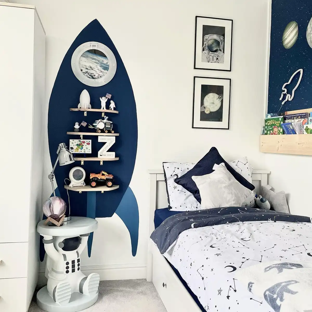 Space-themed bedroom with rocket-shaped bookshelf, simple bed, and small planet decorations