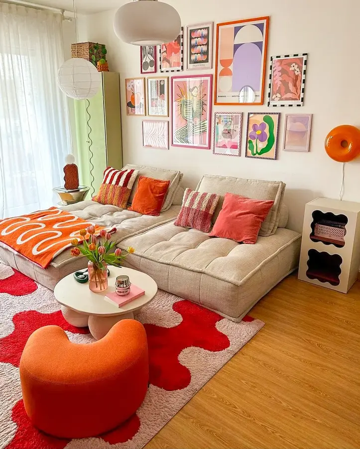 Colorful living room with neutral sectional, orange chair, orange throw and cushions, gallery wall, and pastel accents