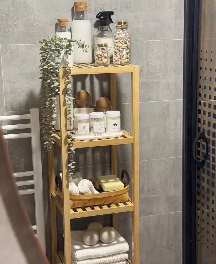 17 Narrow bamboo bathroom shelf with folded towels, baskets, bottles, and trailing plant