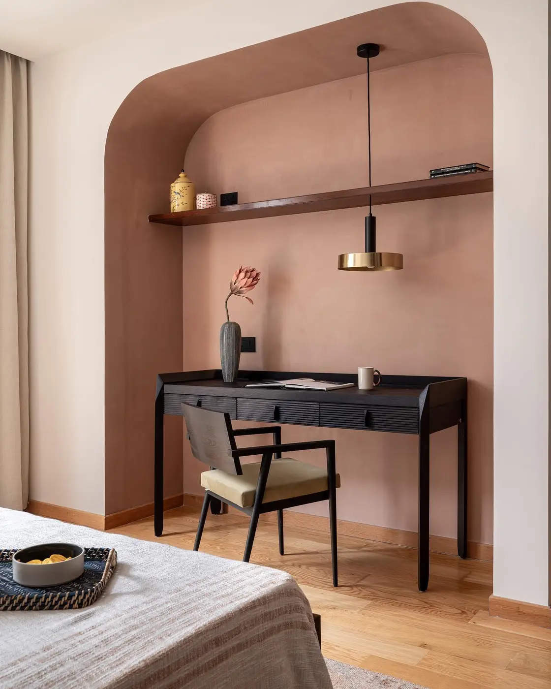 Narrow homework desk in a bedroom alcove with hanging pendant light and floating shelf