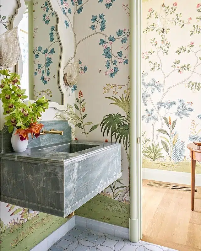 Soft botanical bathroom with delicate garden mural, stone sink, curved mirror, and muted neutral tones
