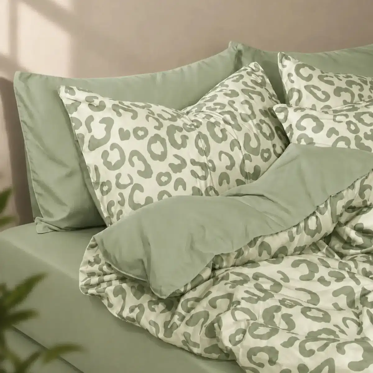 Sage green leopard print bedding with matching green sheets and a soft cream background