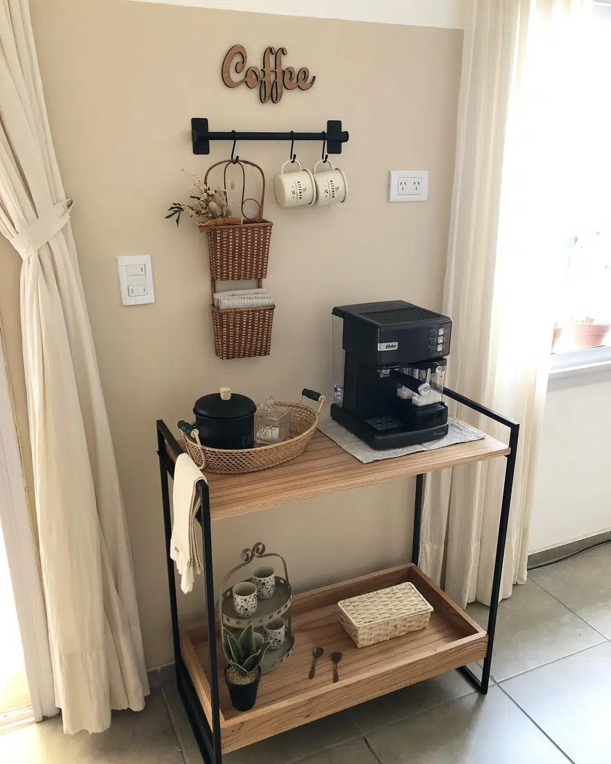 Small farmhouse coffee bar on a narrow console with coffee machine, wall-mounted mug rail, hanging baskets, and lower shelf storage