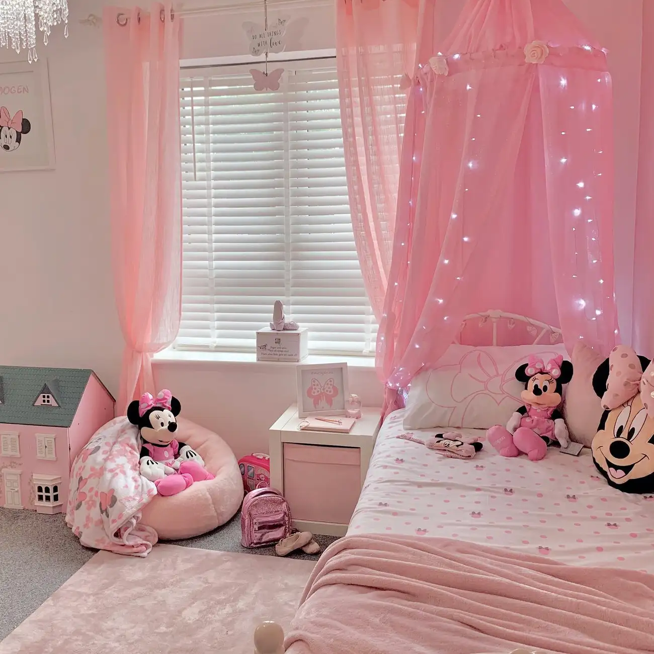 Pink girls bedroom with bright canopy, Minnie Mouse bedding, dollhouse, pale rug, and layered pink shades