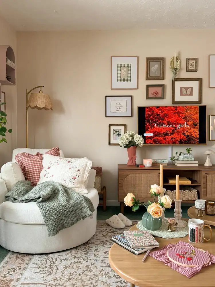 Cozy small living room with one oversized cream chair, gingham cushions, sage throw, and surrounding greenery.