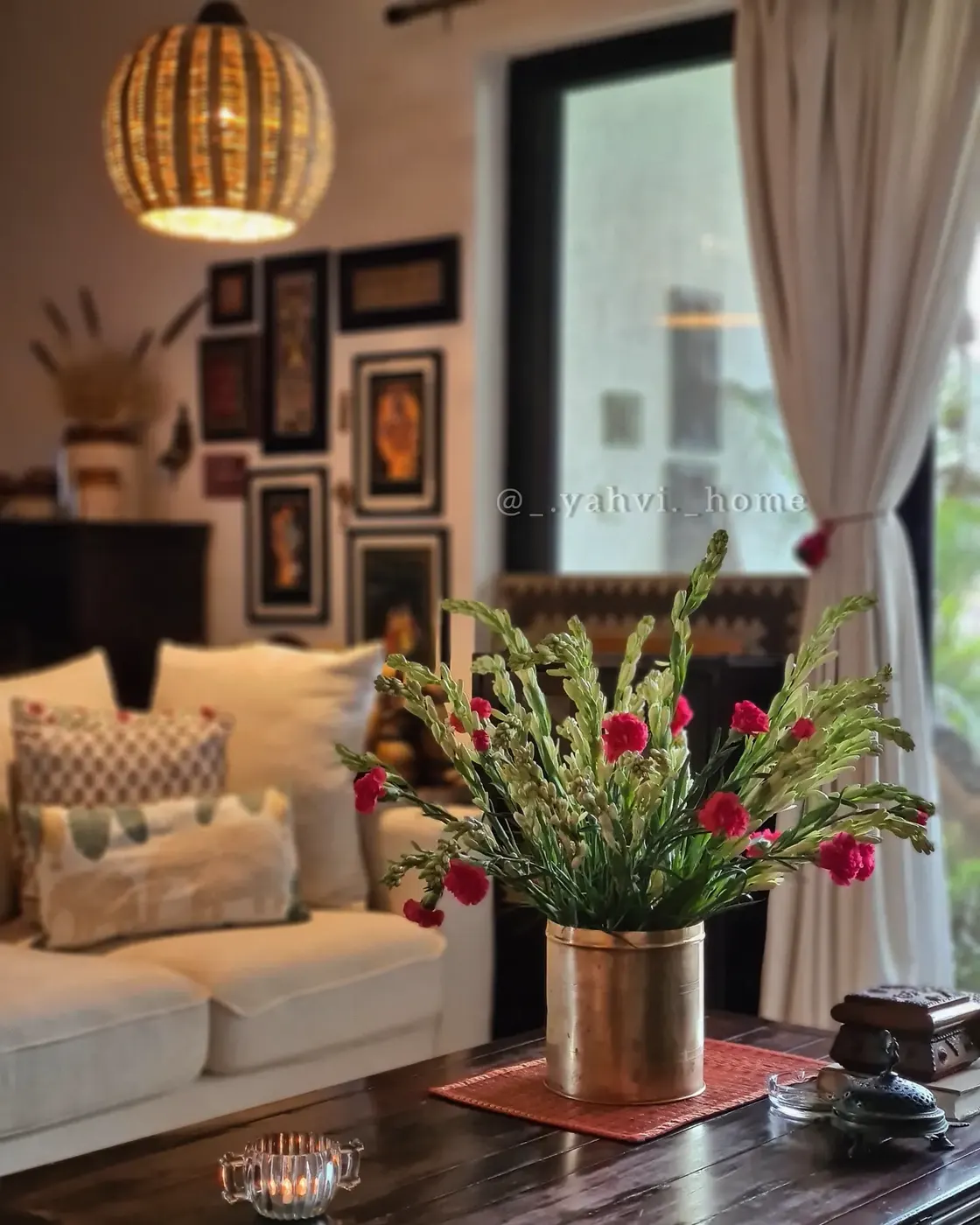Dark wood coffee table with brass vase, colorful flowers, small candle, and decorative objects