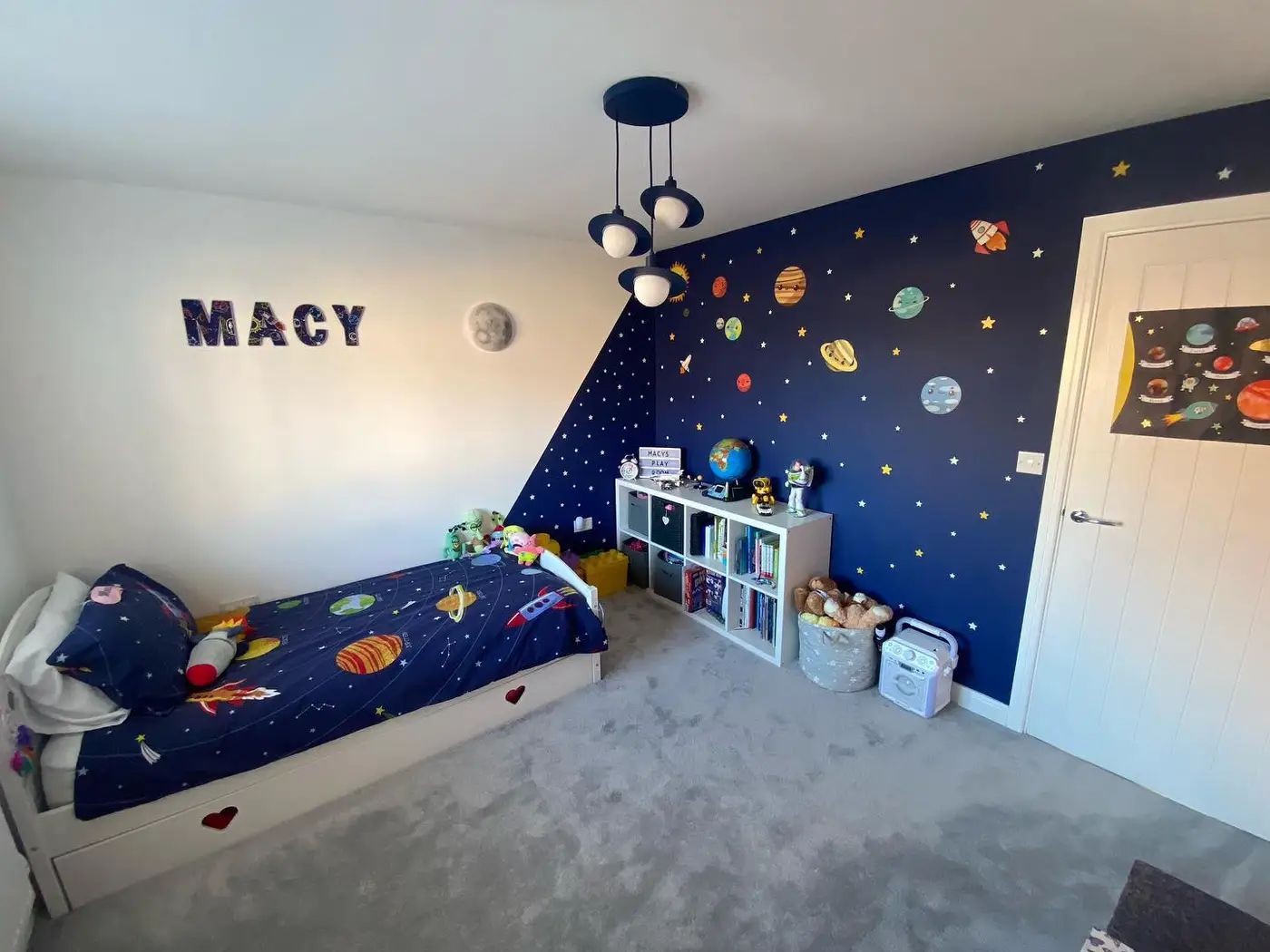 Bright space-themed bedroom with navy planet feature wall, white furniture, and light bedding