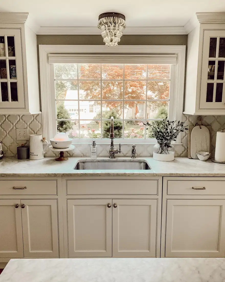 Bright kitchen window with mostly bare sill and leafy decor placed beside the sink