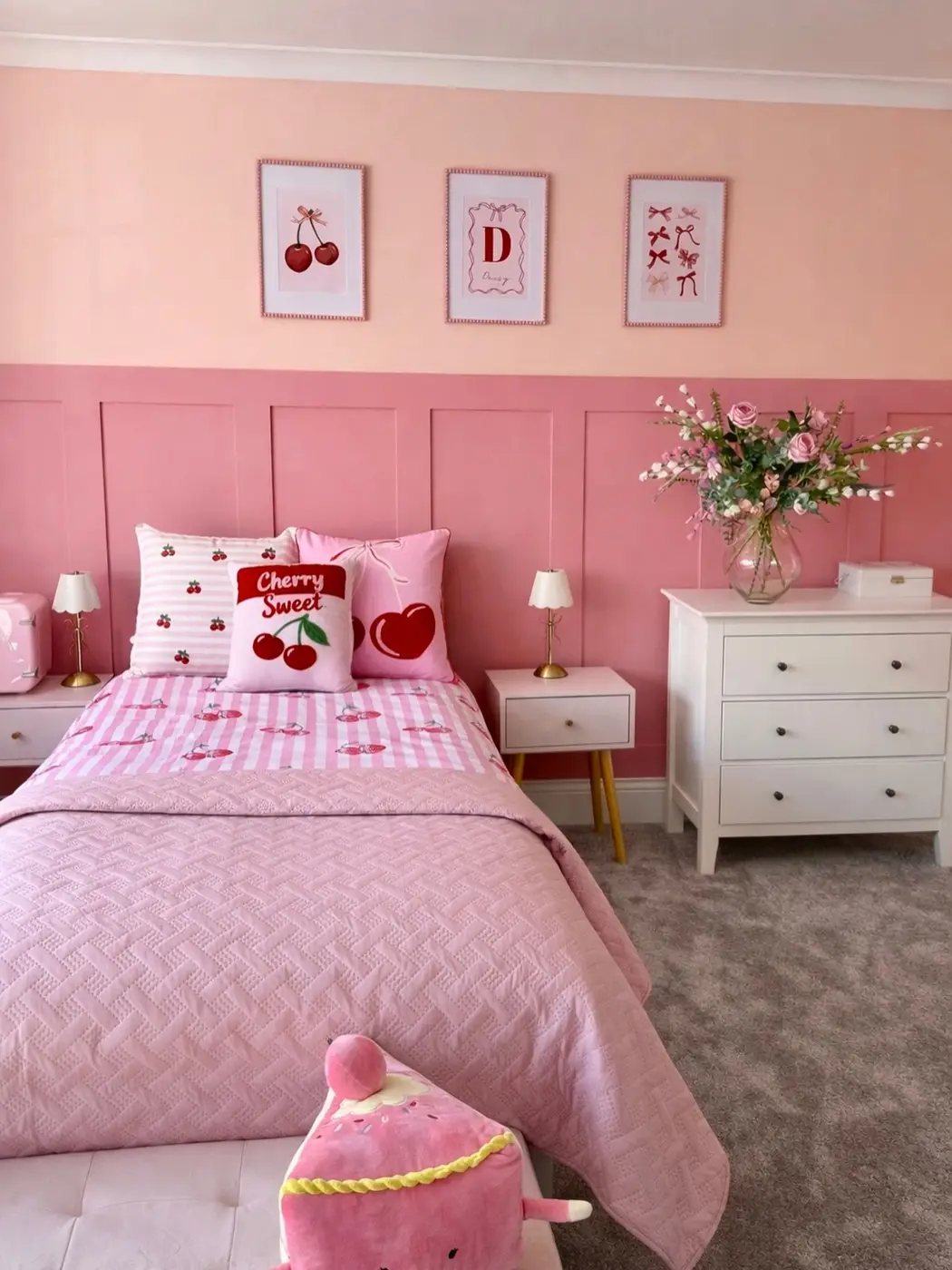 Pink girls bedroom with cherry print bedding, red accents, framed cherry art, and pink wall paneling