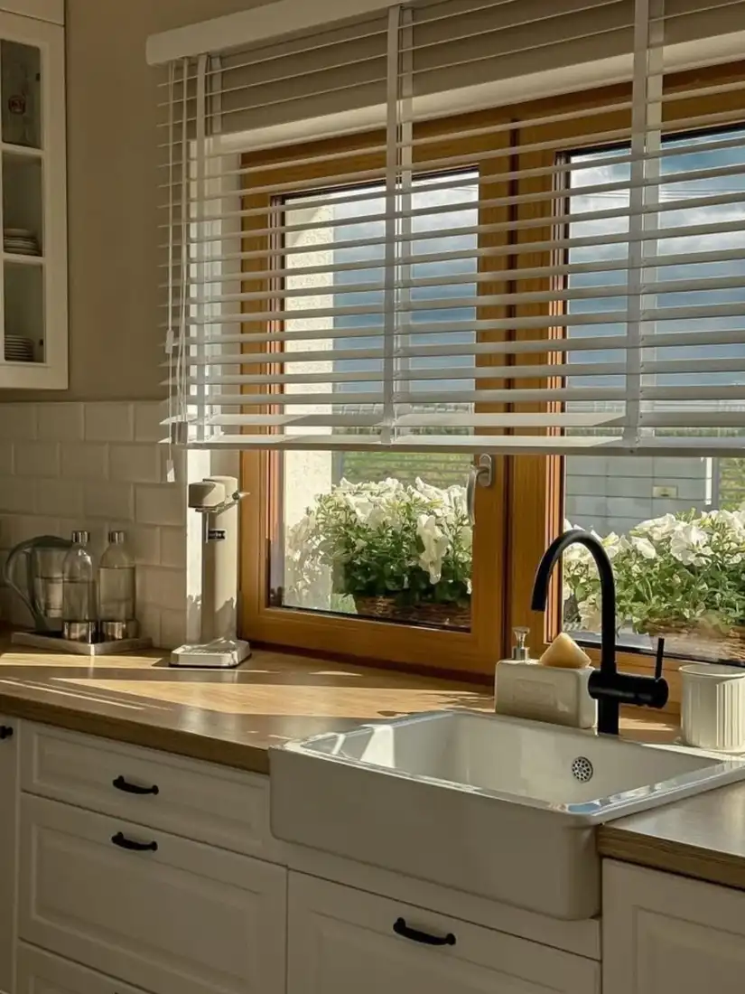 Kitchen window with white flowers blooming outside the glass and a mostly clear indoor sill