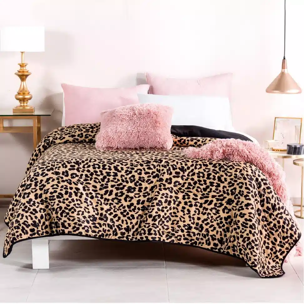 Classic leopard print bedding with blush pink pillows, a pink throw and gold bedside lamps