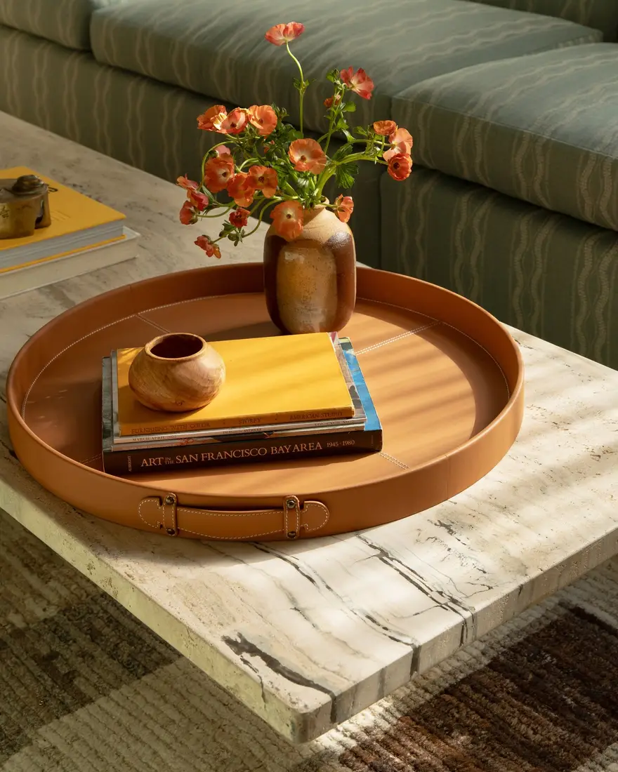 Warm caramel coffee table tray with orange flowers, yellow books, earthy vase, and small wooden bowl