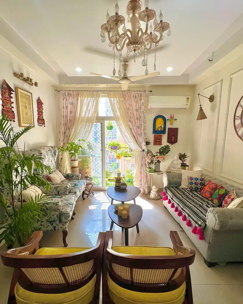 Eclectic living room with yellow cane chairs, floral sofa, gray sofa, mixed bright cushions, plants, and chandelier.