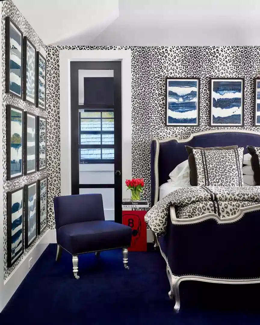 Black and white leopard print bedroom with navy furniture, white bedding and blue wall art
