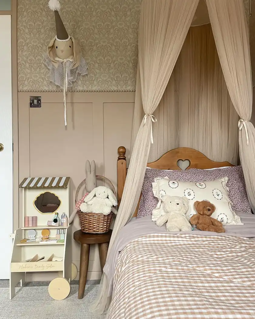 Vintage-style girls bedroom with beige paneling, muted floral wallpaper, wood furniture, gingham, and pale canopy