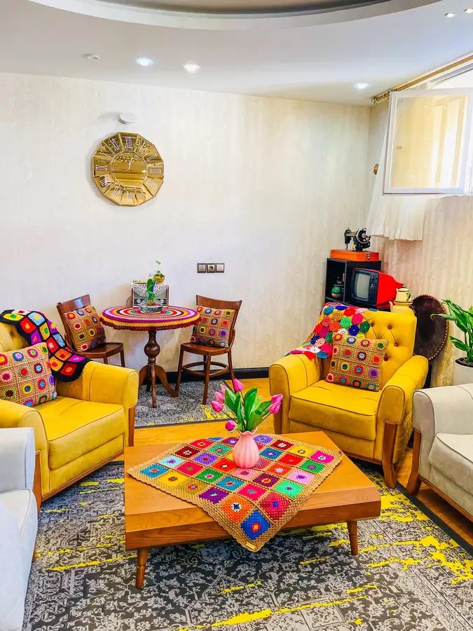 Colorful living room with mustard armchairs, multicolor crochet cushions and throws, bright textiles, and handmade decor