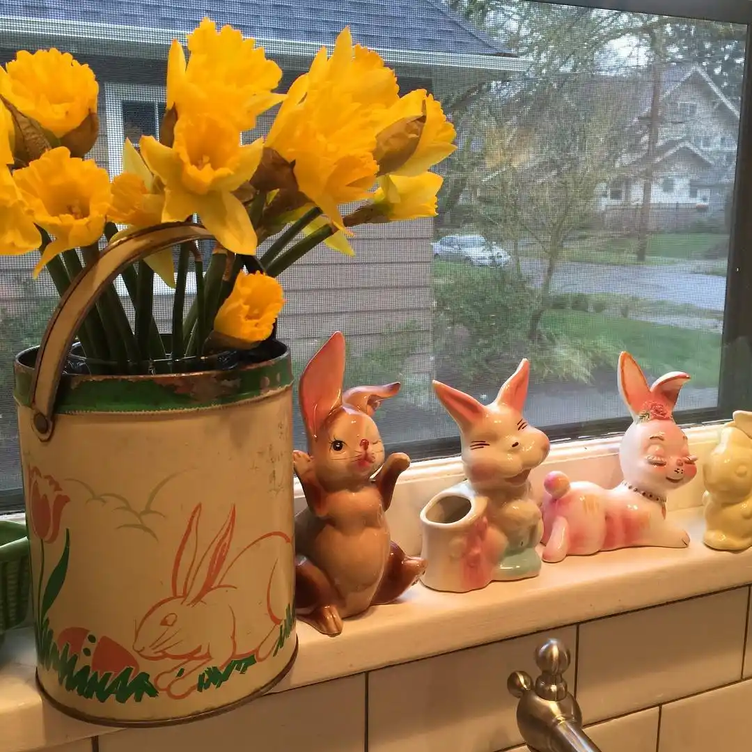 Spring kitchen window sill with bright yellow daffodils and a collection of ceramic rabbit figurines